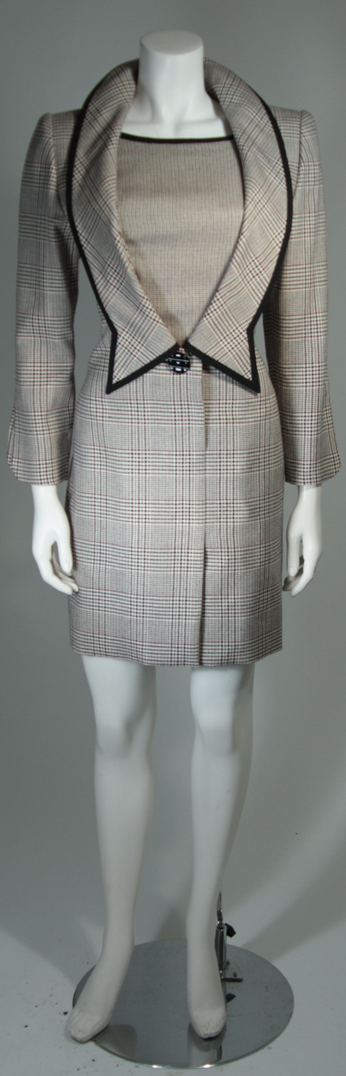 This Galanos Couture dress is composed of a houndstooth patterned wool in hues of maroon, grey, and cream. The coat style dress features center front snap closures and side pockets. In excellent condition.

This is a piece from the personal