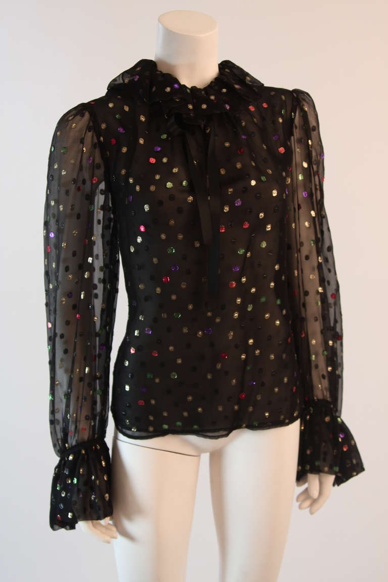 This is a fantastic and fun Yves Saint Laurent blouse. Luxurious silk chiffon fabric is accented with woven metallic red, silver, green, purple, and gold polka dots; the pallet of Yves Saint Laurent. The blouse also features ruffles at the neck as