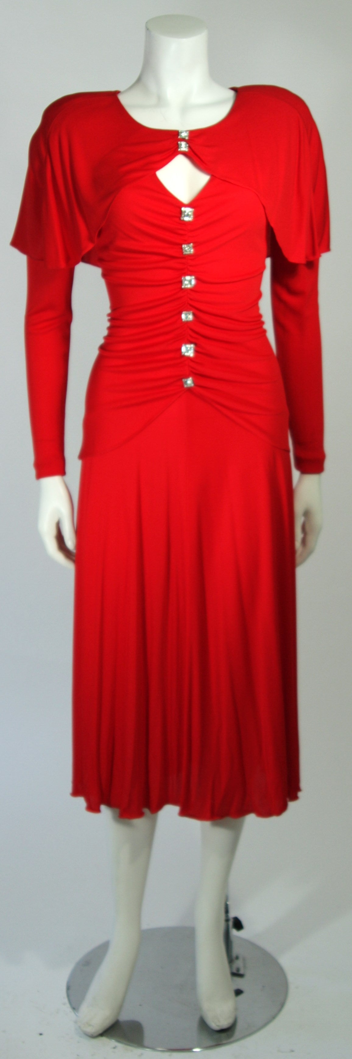 This Holly Harp cocktail dress is fashioned from a superb red jersey. Featuring rhinestone buttons, ruching, and long sleeves, this dress offers a complementing fit. Padded shoulders. In excellent condition.

**Please cross-reference measurements