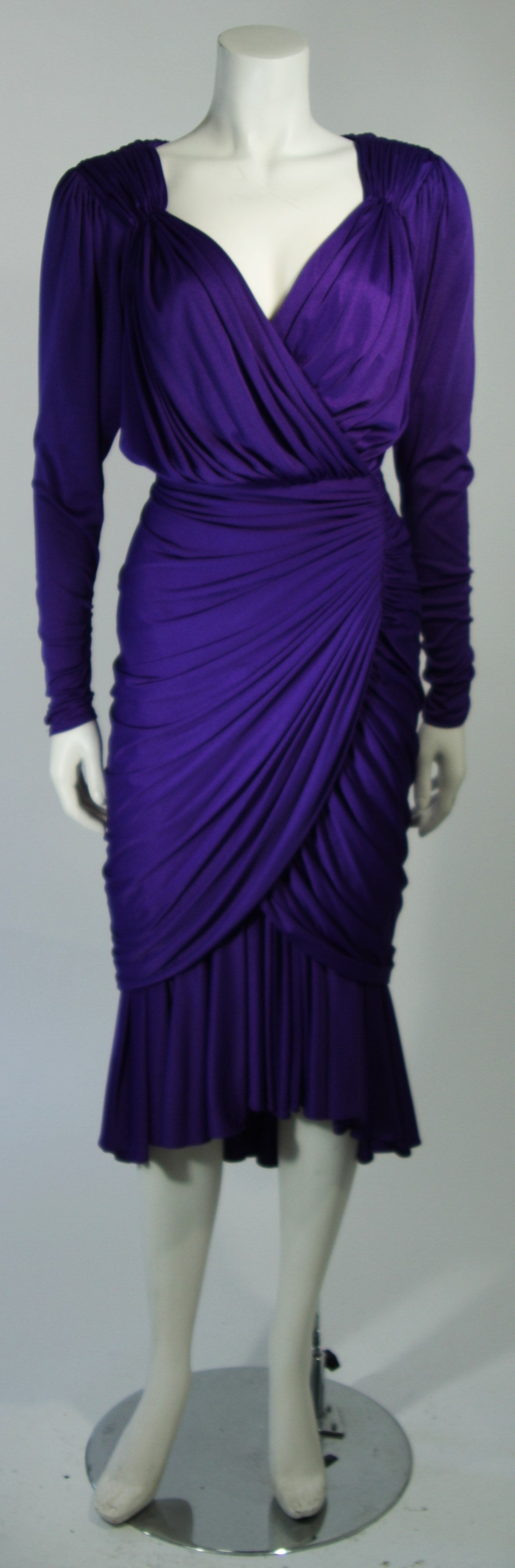 This vintage cocktail dress is fashioned from an purple jersey. Features ruching throughout and a v-neck plunge neckline with a center back zipper. In excellent condition.

**Please cross-reference measurements for personal accuracy. The size