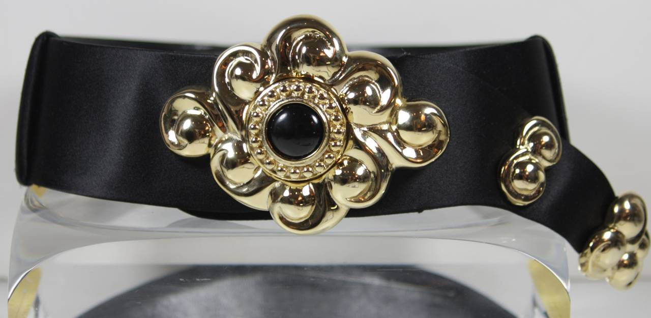 This Judith Leiber belt is composed of a black satin features gold hardware with an inset black hued stone. The belt can be adjusted. In excellent condition. Comes with box.

**Please cross-reference measurements for personal accuracy.

Measures