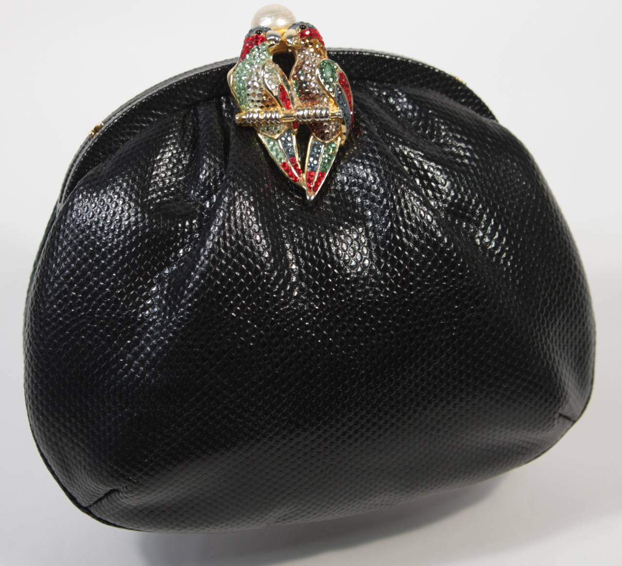 This vintage Judith Leiber handbag is composed of a black lizard and features an embellished parrot clasp topped with a pearl. In excellent condition; comes with original dust bag.

**Please cross-reference measurements for personal