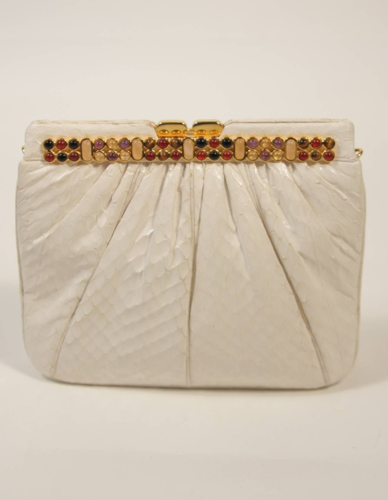 This vintage Judith Leiber handbag is composed of a white gathered snakeskin. The frame style clutch is adorned with multiple colored stones. In excellent condition, there is some slight natural yellowing of the skin in certain areas, due to age.