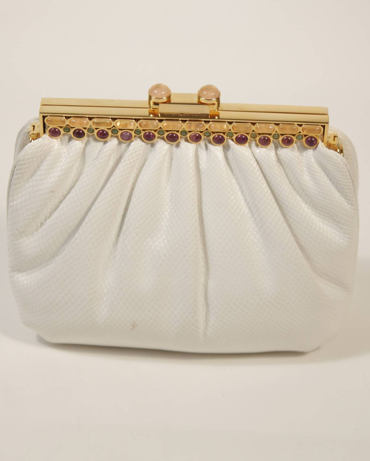 This vintage Judith Leiber is available for viewing at our Beverly Hills Boutique. We offer a large selection of evening gowns and luxury garments.

This handbag is composed of gathered white lizard. The gold metal frame is adorned with