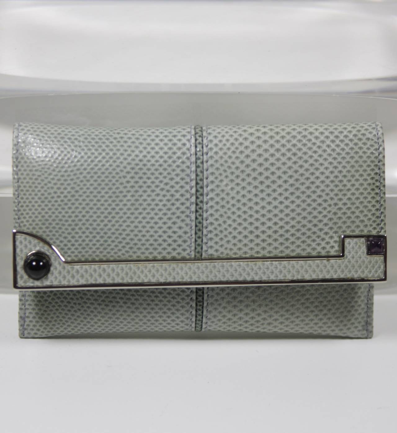 This vintage Judith Leiber is available for viewing at our Beverly Hills Boutique. We offer a large selection of evening gowns and luxury garments.

This wallet is composed of a bluish grey lizard skin and features silver hued details. There is an