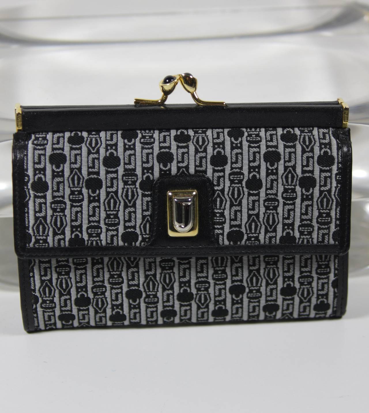 This vintage Judith Leiber is available for viewing at our Beverly Hills Boutique. We offer a large selection of evening gowns and luxury garments.

This wallet is composed of black and silver printed fabric. The interior is leather. There is a