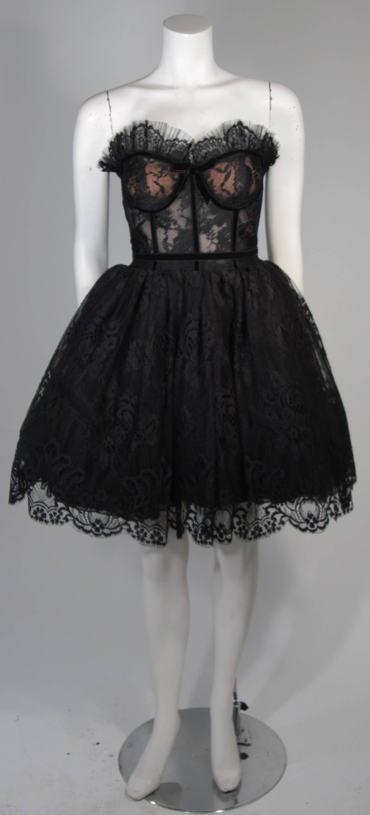 This vintage cocktail gown is composed of black lace and features scalloped edges as well as velvet trim. There are layers of crinoline for add volume and a structured bodice with boning. There is a center back zipper closure. In excellent