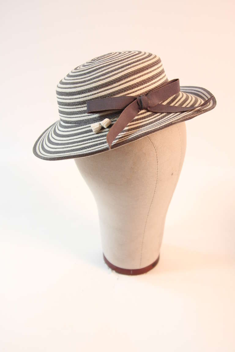 This is a beautiful Christian Dior hat. This hat is excellently crafted and exquisitely woven. The hat is circa 1960's, it features two hat pins, and a beautifully placed ribbon. It is a wonderful combination of slate grey and off white.