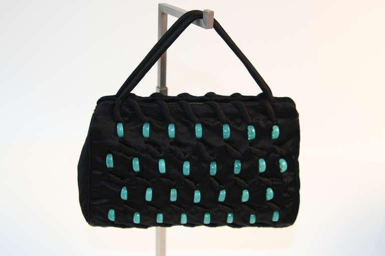 This is a beautiful Volokhoff purse. The purse features a wonderful turquoise large bead pattern. There are two straps with a zipper closure. The fabric is a wonderful black silk. Made in France. Circa 1940's.

Measures (approximate)
Height: