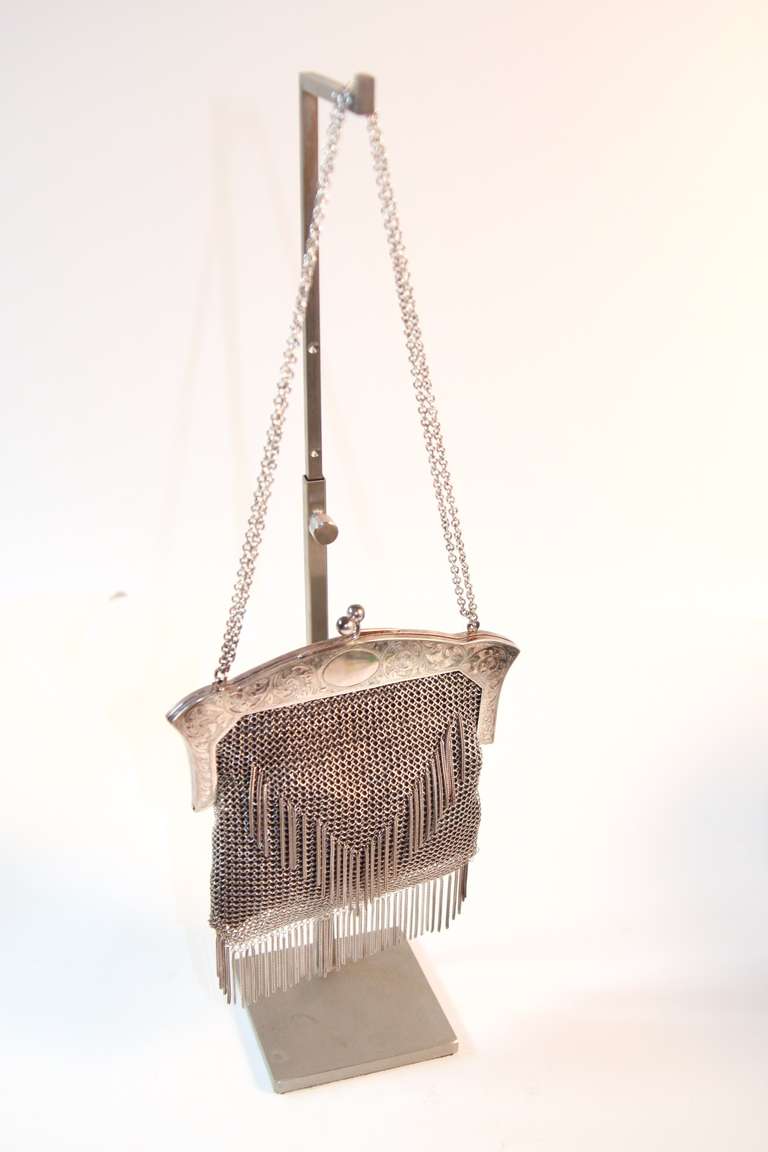 This is an incredible Sterling silver purse. The purse features mesh chain metal and a fringe design. The frame is in etched with floral leaf motifs. This bag is a stunning accessory. It comes with documentation of it's authenticity. The handbag is
