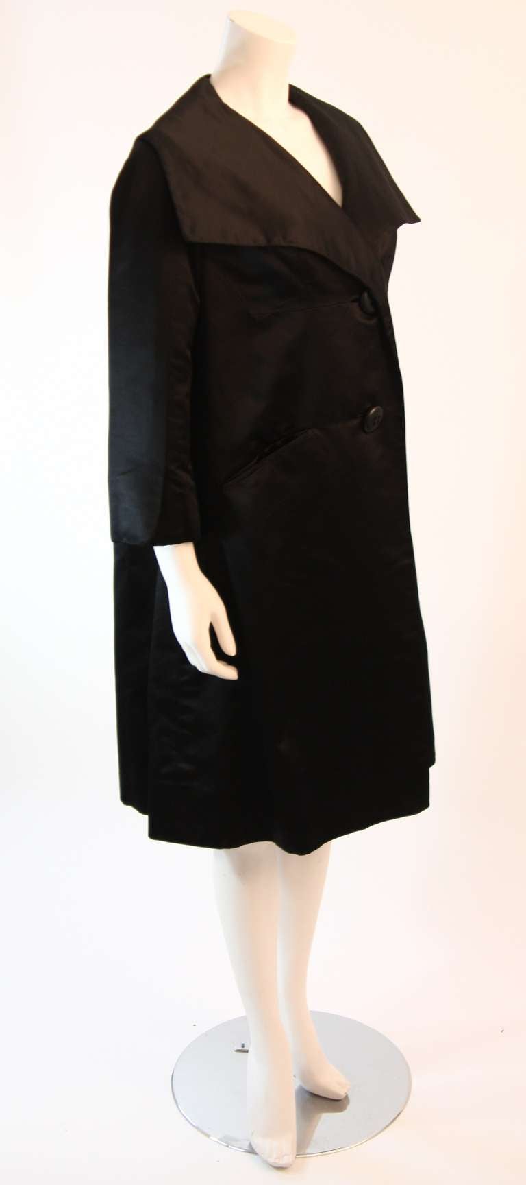 This is a Galanos original coat. This wonderful early 1960's opera coat is composed of a beautiful supple black silk. It features 3/4 bracelet length sleeves, two front welt pockets, two button closure, and a perfectly proportioned over exaggerated