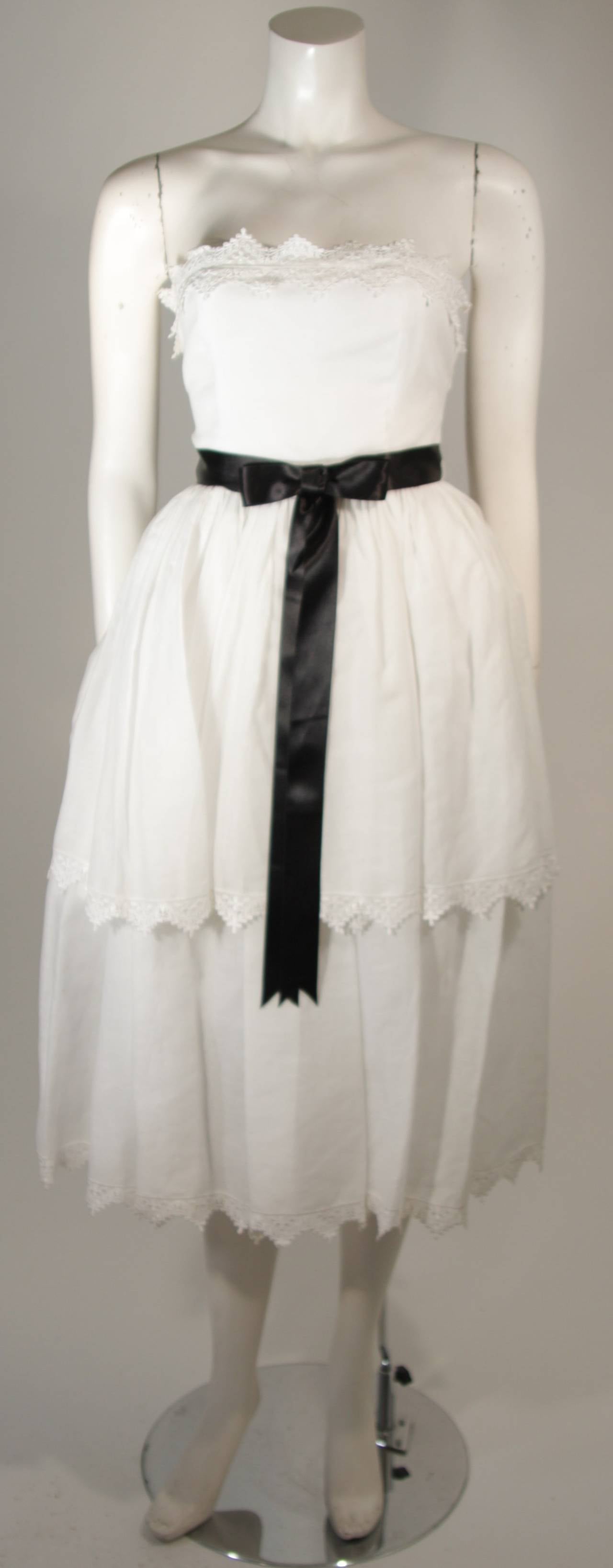 Dieses Kleid von Albert Capraro besteht aus weißer Baumwolle und hat einen Spitzenbesatz. Es gibt einen Reißverschluss in der Mitte des Rückens. In ausgezeichnetem Zustand. 

**Bitte vergleichen Sie die Maße für Ihre persönliche Genauigkeit. Die