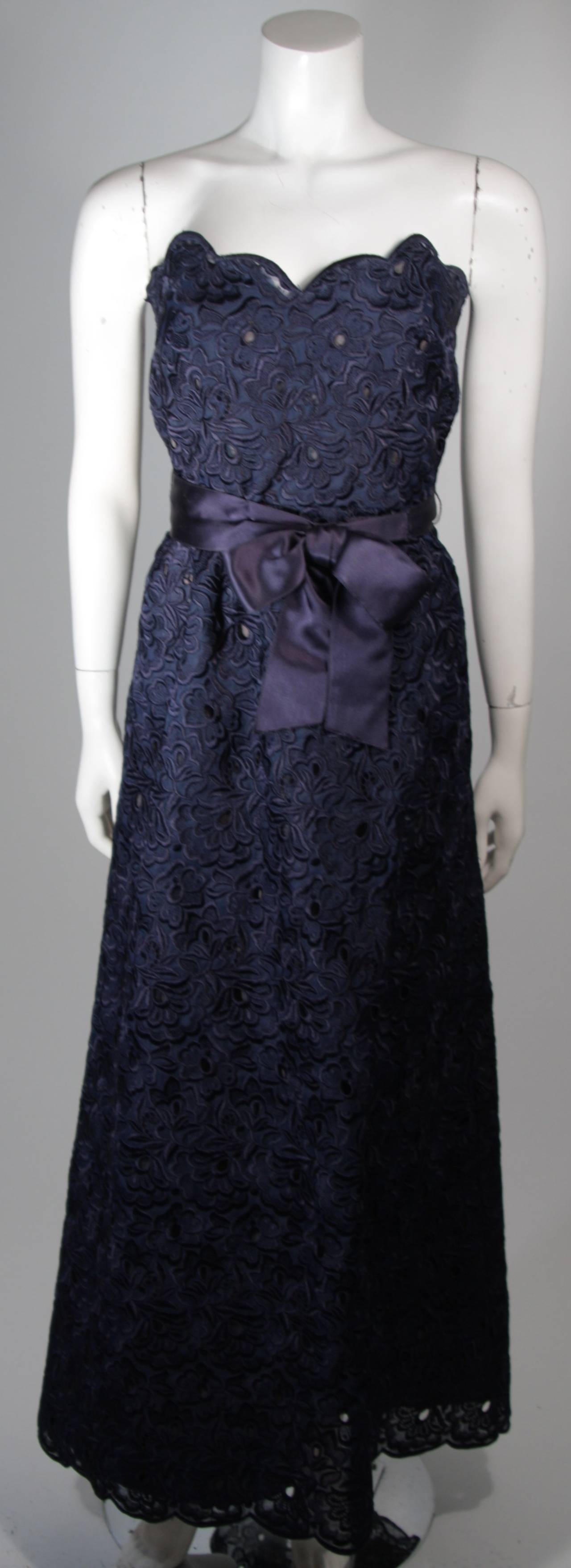 Dieses Kleid von Scaasi ist aus marineblauer Spitze gefertigt und mit einem Gürtel aus Satin versehen. Die Tasche ist mit einem Reißverschluss versehen. In ausgezeichnetem Zustand. Hergestellt in den U.S.A. 

**Bitte vergleichen Sie die Maße für