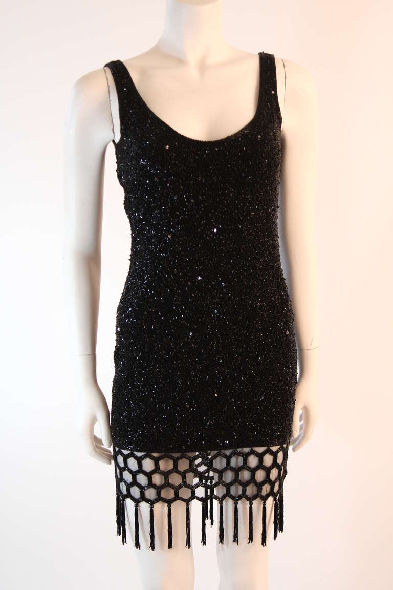 This is a stunning Naeem Kahn cocktail dress. This cocktail dress features heavy black beading and sequins. The dress has a lower scoop back and a sheer lattice design hem with beaded fringe. 
Center back zipper closure.
 Naeem Kahn
 