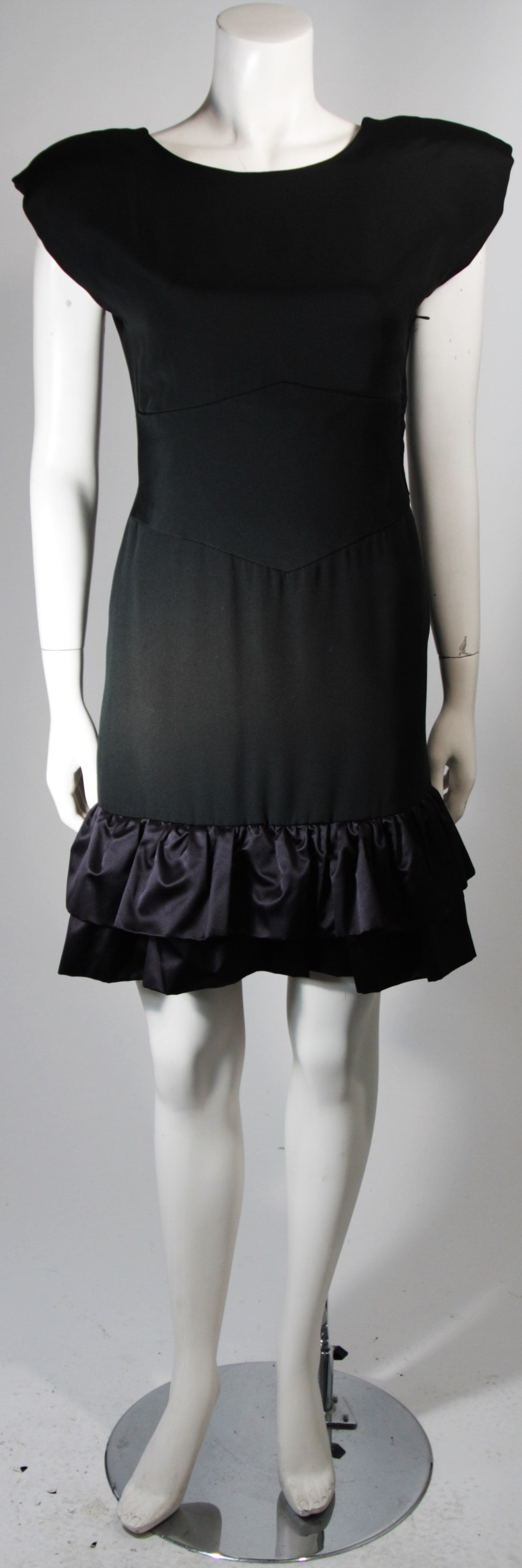 This Vicky Tiel dress is composed of a black silk and features a satin ruffled hem. There is a scoop style back with criss-cross accents and a side zipper closure for ease of access. In excellent condition. Made in France.

This item is from the