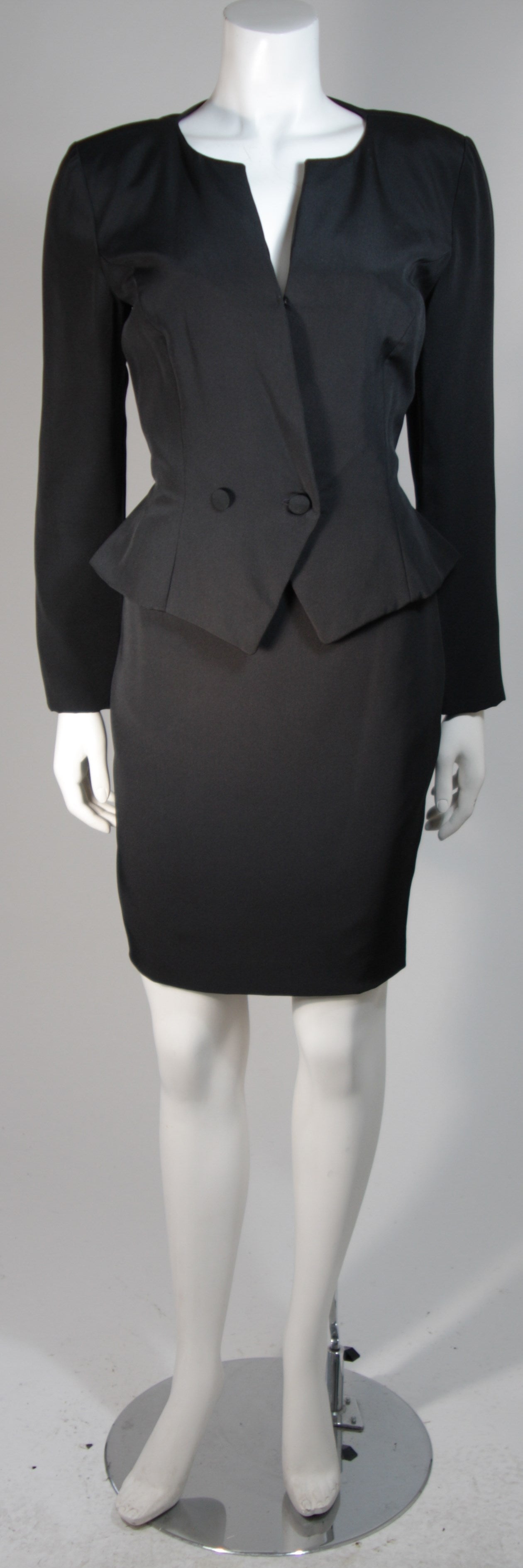 This Vicky Tiel suit is composed of a black silk and features a lace panel on the back of the jacket. The jacket features a center front button fastening. There are two a pencil silhouette style skirts with zipper closures. In excellent condition.