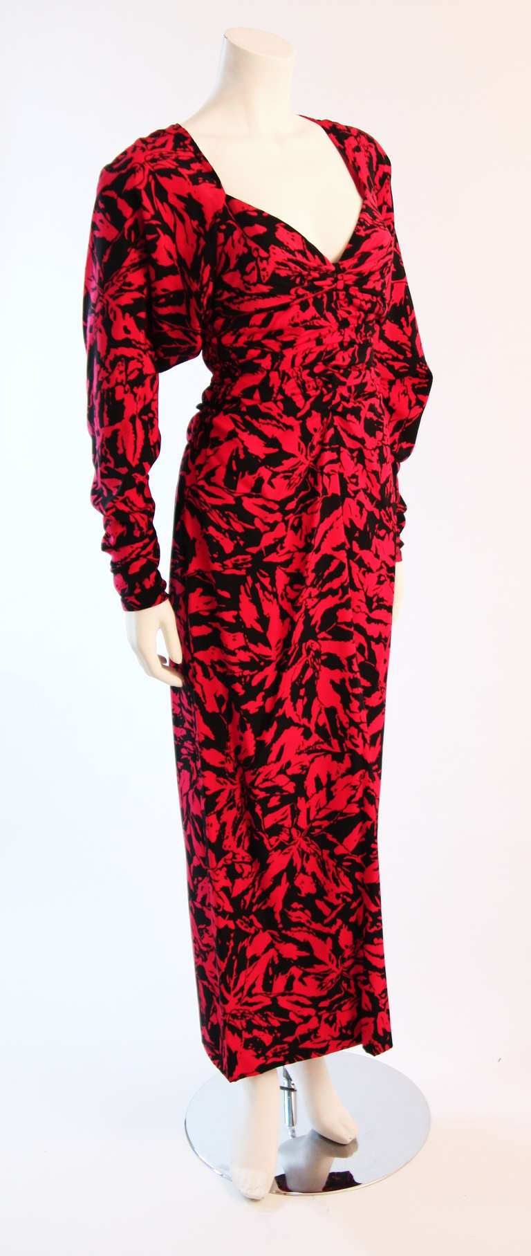 This is a Nina Ricci Haute Boutique gown. This gown is composed of a black and red abstract patterned silk. It features ruched details along the bust, sleeves, and shoulders. There is a zipper closure along the center back and sleeves. An absolute