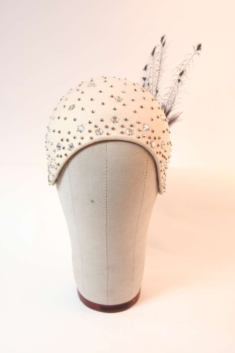 This is an absolutely amazing Adolfo Realities hat. The rich creamy wool is accented by a bursts of faceted rhinestones, studs, and finished with silver & white tipped peacock feathers.
 This hat is what dreams are made of, simply beautiful.
Made