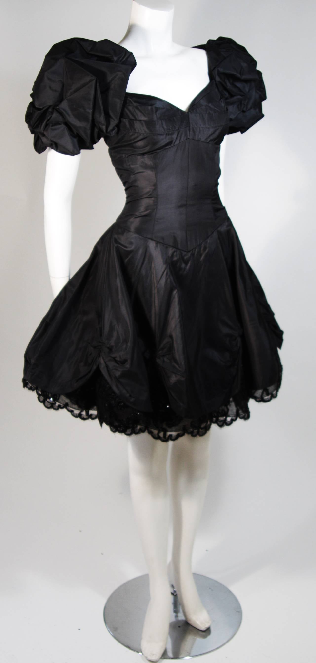 This Vicky Tiel gown is composed of a black silk and features a draped skirt with sequined lace accents. The bodice features boning for structure and there is  a center back zipper closure for ease of access. In excellent condition. Made in