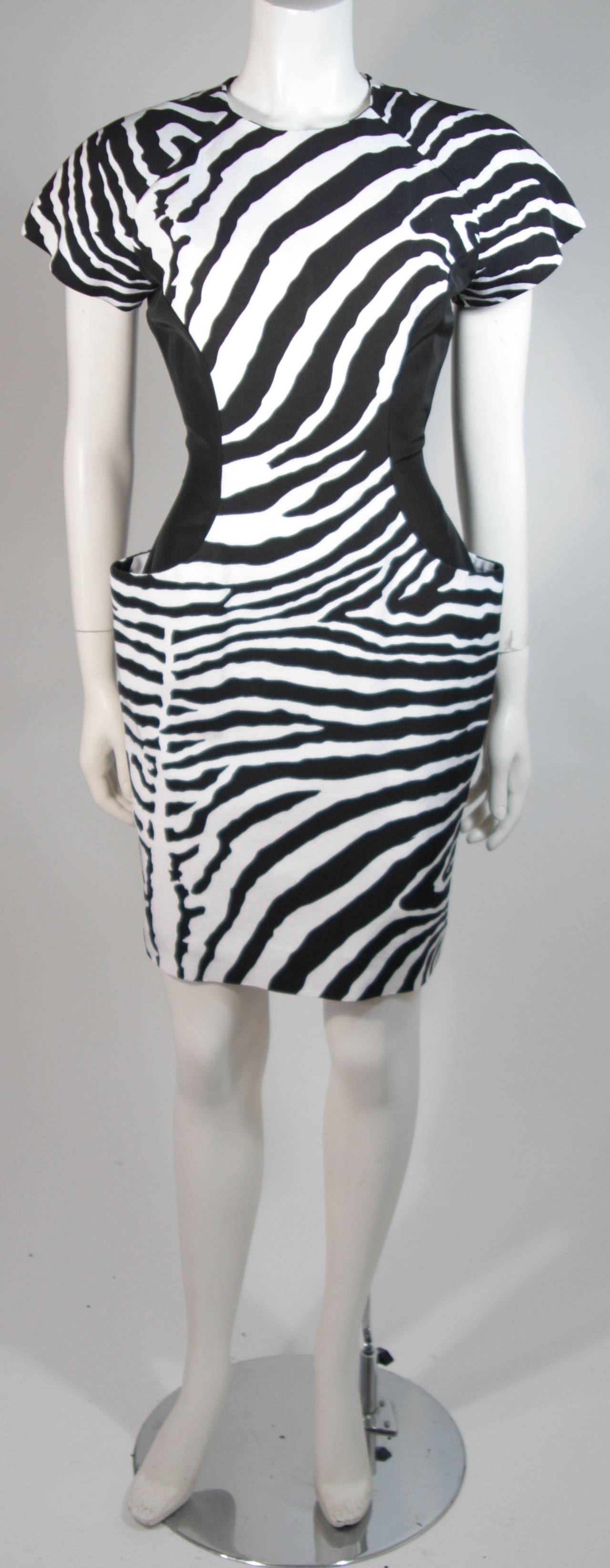 This Vicky Tiel cocktail dress is composed of a black and white zebra print fabric and a side panel color block in black. There are princess seam pockets on the front. There is a center back zipper closure for ease of access. In excellent condition.
