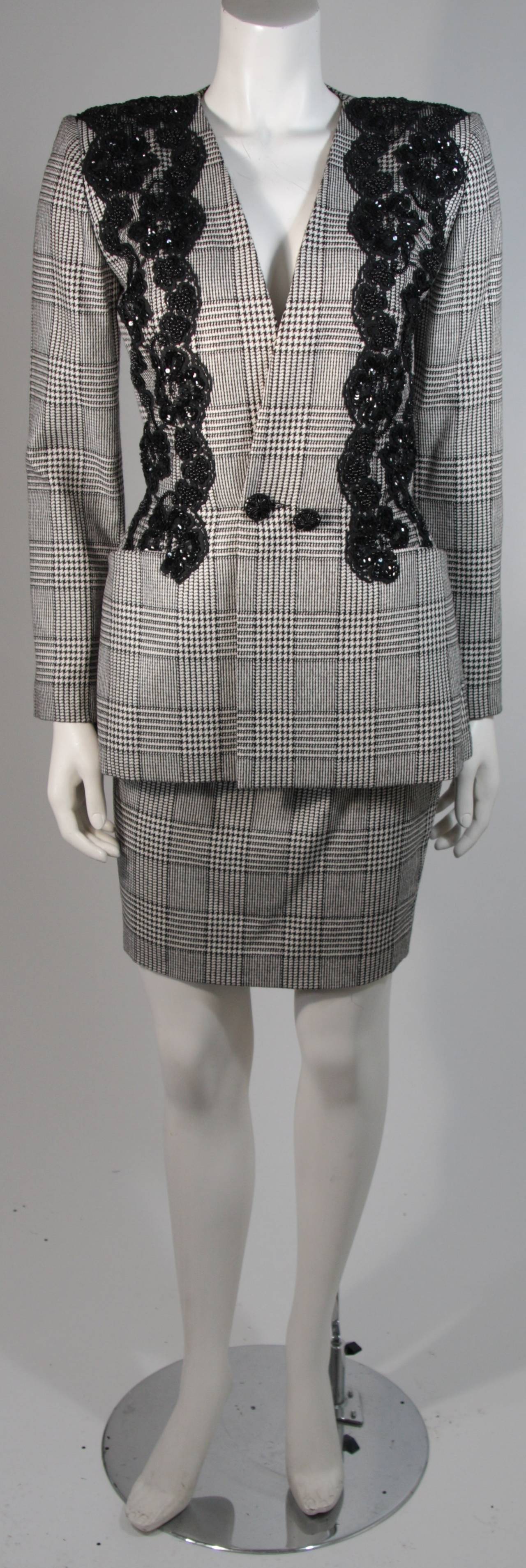 This Vicky Tiel skirt suit is composed of a black and white houndstooth print silk and features beaded lace applique on the jacket. The jacket has a center front button closure and the skirt has a center back zipper closure for ease of access. In
