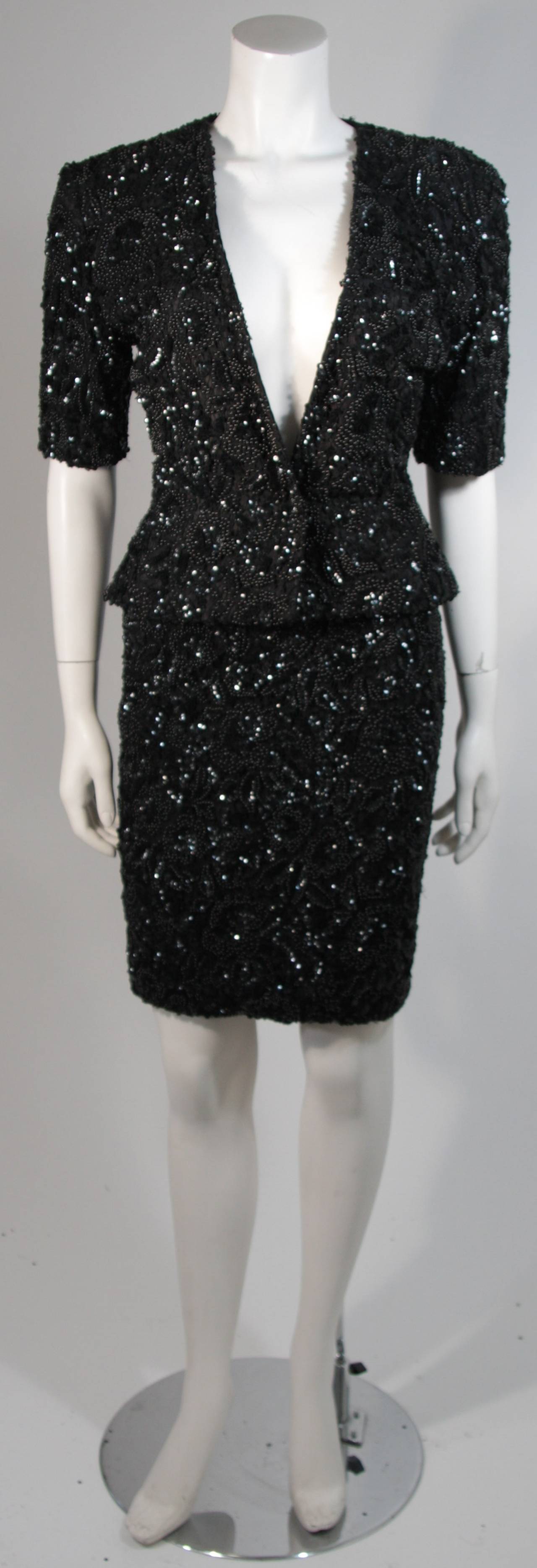 This Vicky Tiel skirt suit is composed of a black sequin and beaded lace. The jacket features a center front snap closure and the skirt has a center back zipper closure for ease of access. In excellent condition. Made in France.

This item is from