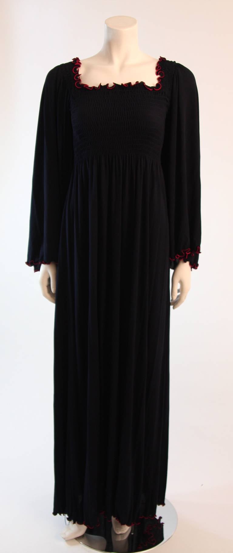 This a wonderful Vicky Tiel design. This dress is composed of a navy stretch fabric with red accenting at the neck. The dress can be worn on or off the shoulders. Features a stretch ruching detail at the bust and waist. Bell sleeves. Made in France.