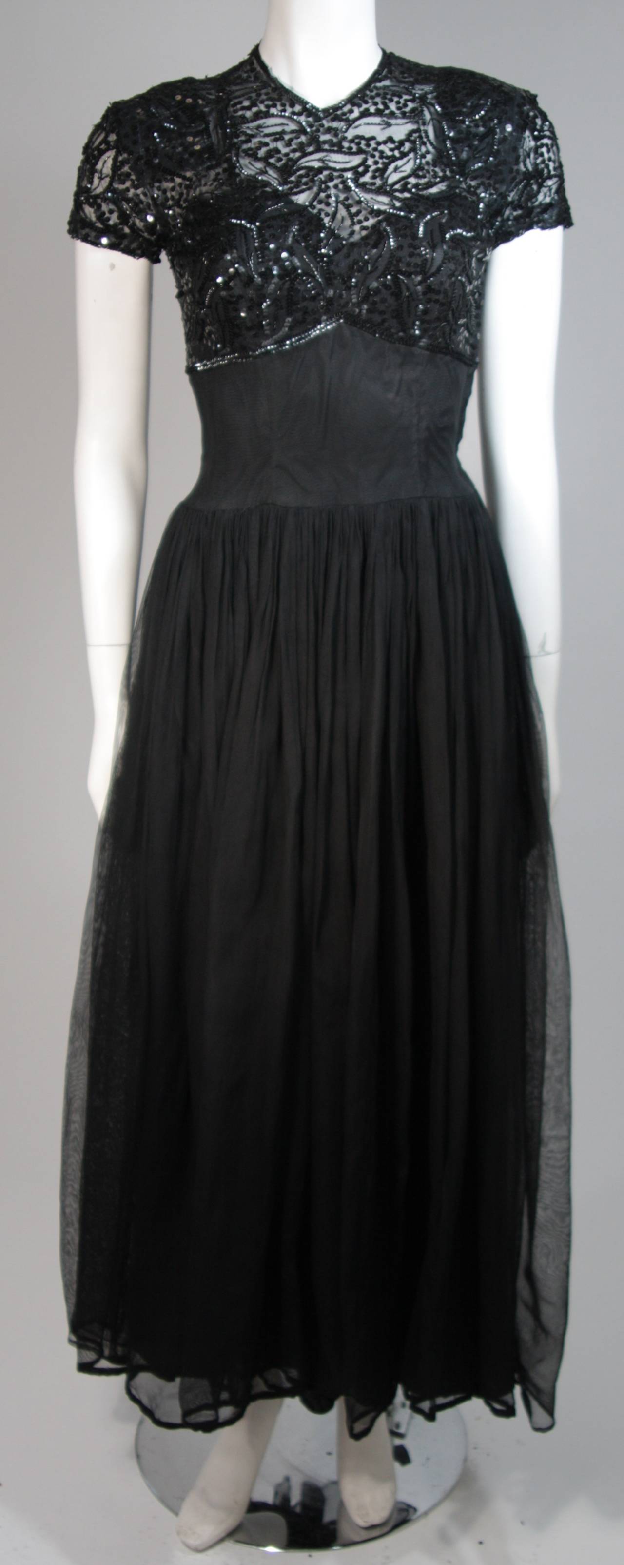 This Ceil Chapman gown is composed of a black chiffon skirt and features an upper beaded lace bodice. The dress has an empire waist with a full gathered skirt. In excellent vintage condition, the label is not present. Beautiful for design