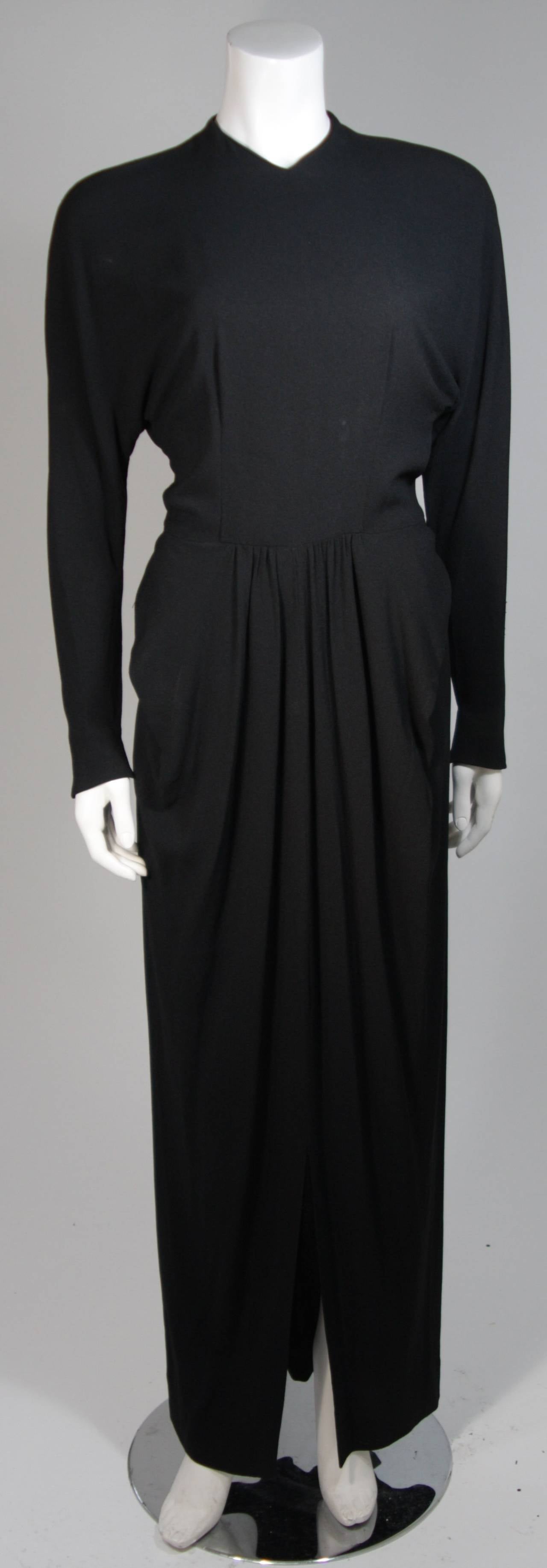 This Ceil Chapman gown is composed of a black silk crepe. The dress features center front draping at the waist and draped bat-wing style sleeves. There are center back buttons and a slight keyhole opening. In excellent vintage condition. Beautiful