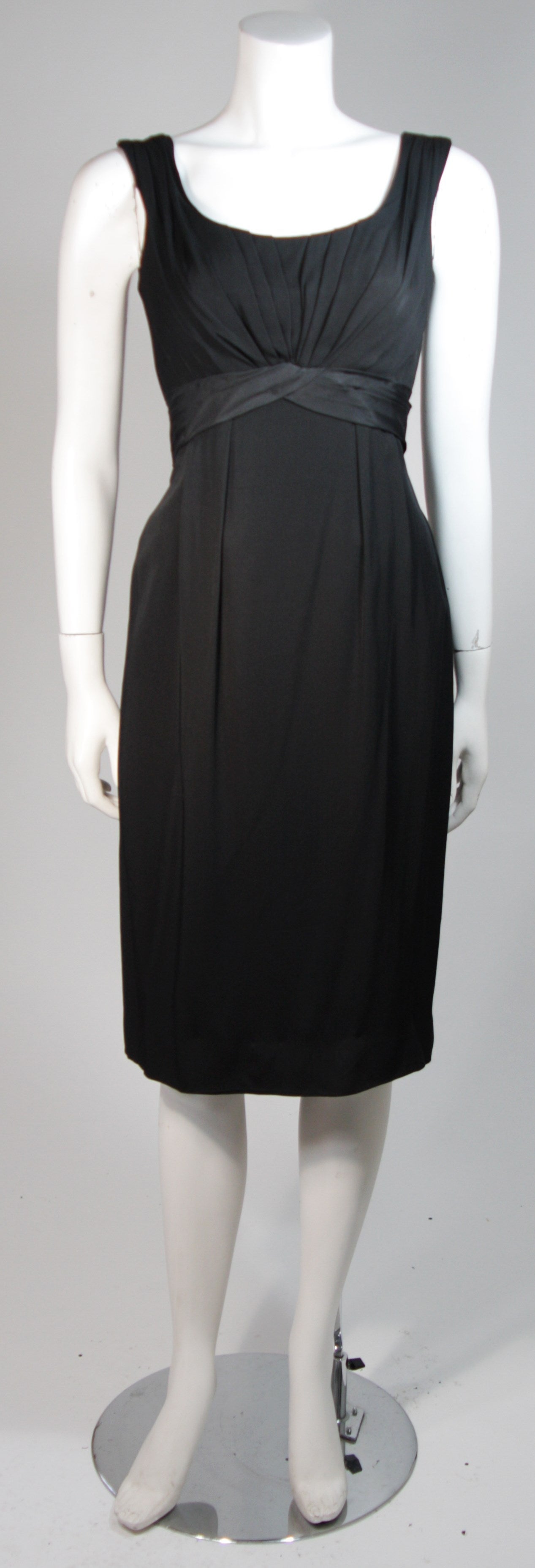 This Ceil Chapman cocktail dress is composed of a black silk. The dress features draping at the center front and a center back zipper. There is a sash detail at the center back waist. In excellent vintage condition. Beautiful for design inspiration.