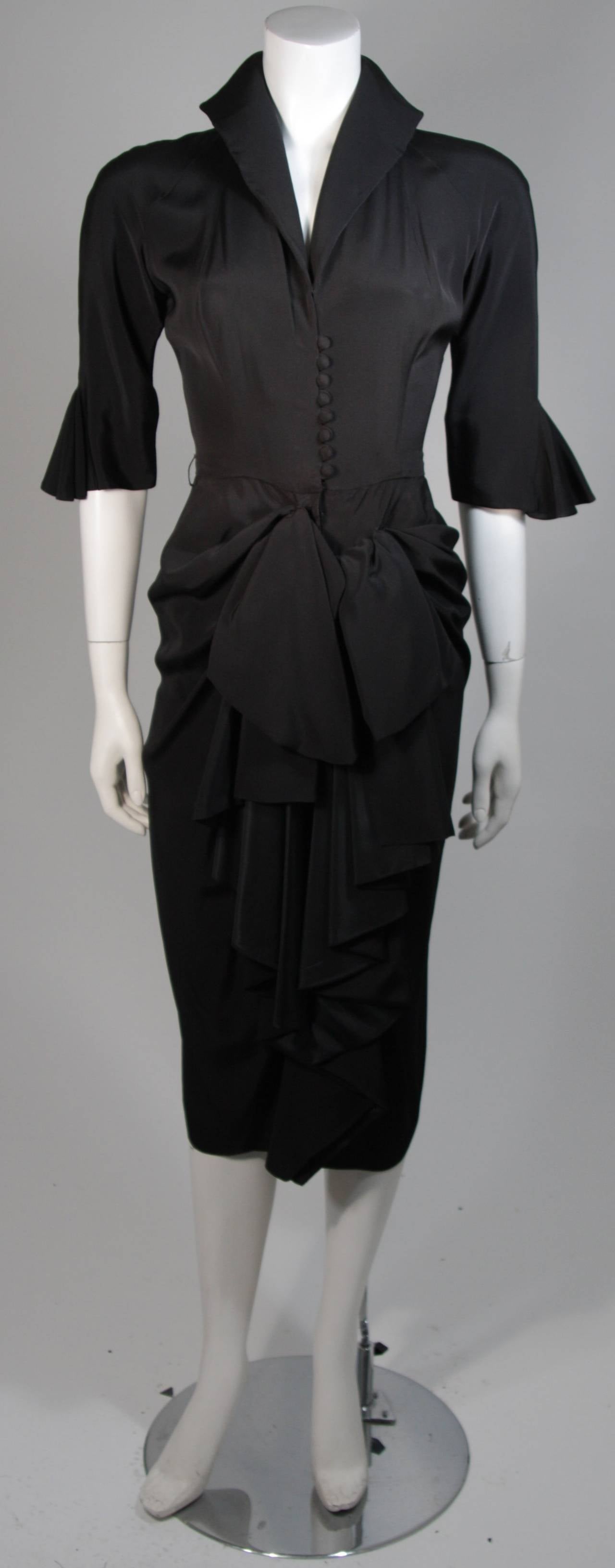 This Ceil Chapman cocktail dress is composed of a black rayon. The dress features center front button closures and a zipper. There is a center front draping at the waist. In excellent vintage condition. Beautiful for design inspiration. 

**Please