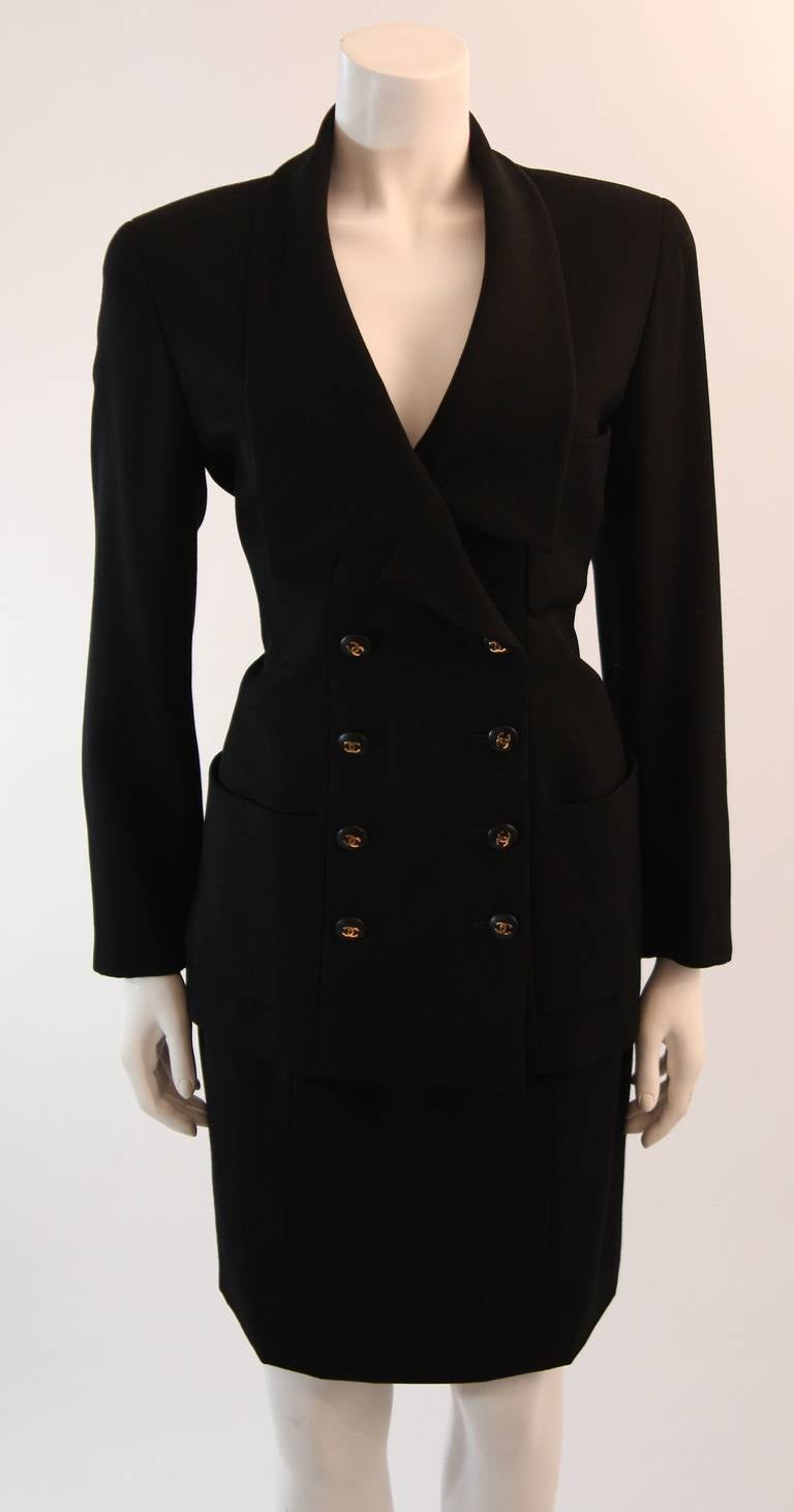 This is a beautifully designed Chanel skirt suit. The jacket features a wonderful double breast design with shawl-draped neckline, and two front pockets. There are Chanel logo buttons at the center front and sleeves. The skirt is a classic Chanel