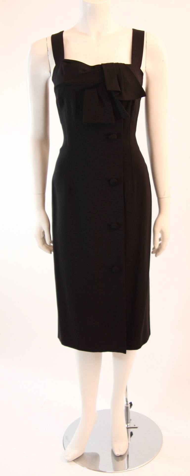 Dies ist ein wunderschönes COUTURE Pierre Balmain Kleid. Das Kleid ist aus einem wunderschönen schwarzen, schweren Leinen gefertigt. Dieses Dreiviertelkleid ist mit einer drapierten Schleife auf der Vorderseite und seitlichen Knöpfen verziert.