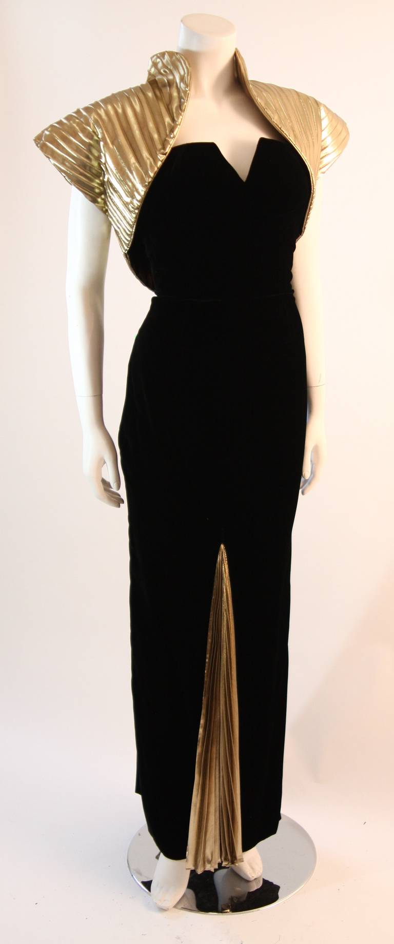This is a stunning Vicky Tiel gown. The gown is composed of a beautiful black velvet and is accented with a wonderful metallic gold accordion material. The chic bolero adds the perfect amount of personality to the piece. Amazing design. 

Measures