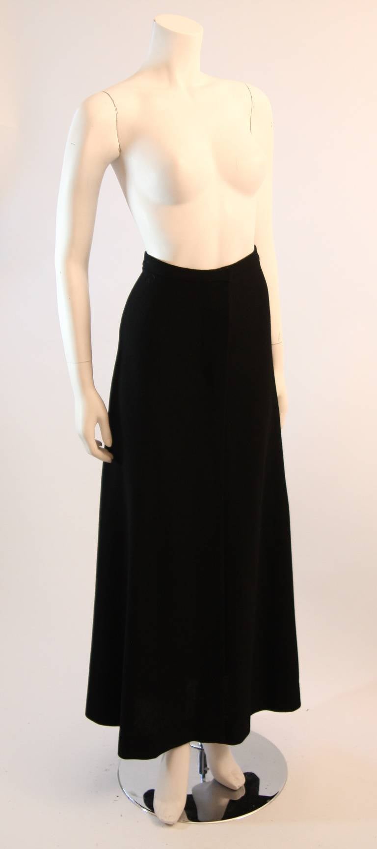 This is a gorgeous Halston maxi skirt. It is composed of a perfect stretch knit in black with a full swooping flare. An absolute stunner. The skirt features snap  closures and a slit at the center front. 

Measures (Approximately)
Size