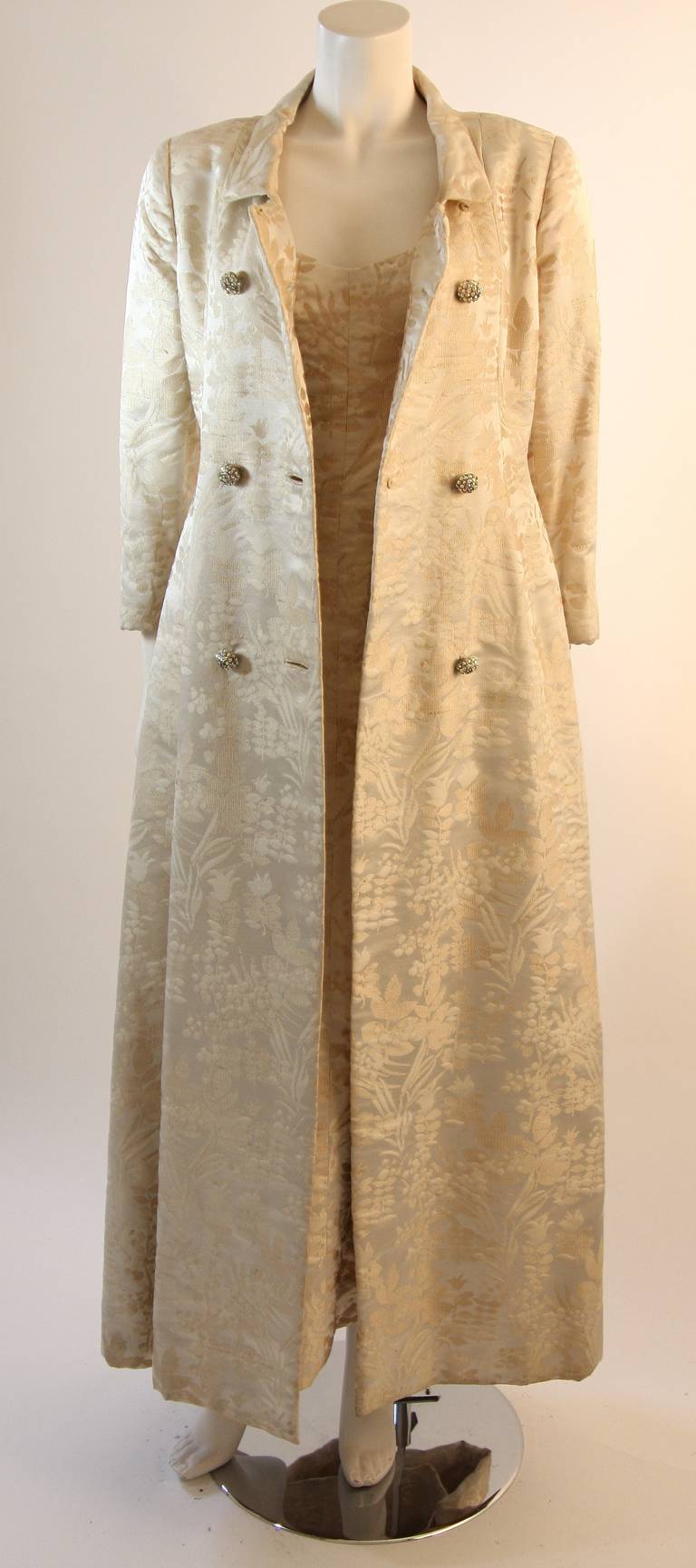 This is a Ben Zuckerman for Amelia Gray of Beverly Hills design. This set features two pieces, a wonderful full length dress and beautiful evening coat. The set is composed of a fabulous cream and off white brocade fabric. The double breast coat is