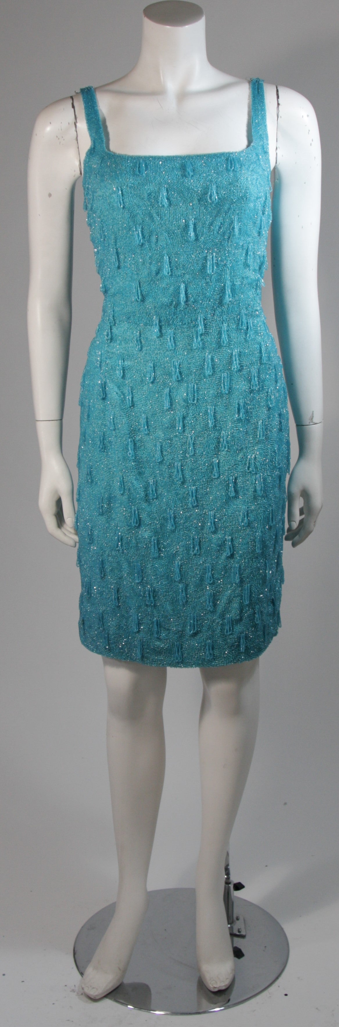 This vintage cocktail dress features heavy beading in an aqua hue with a drape accent of some of the beading. An absolutely stunning piece. There is a center back zipper. In excellent condition. 

**Please cross-reference measurements for personal