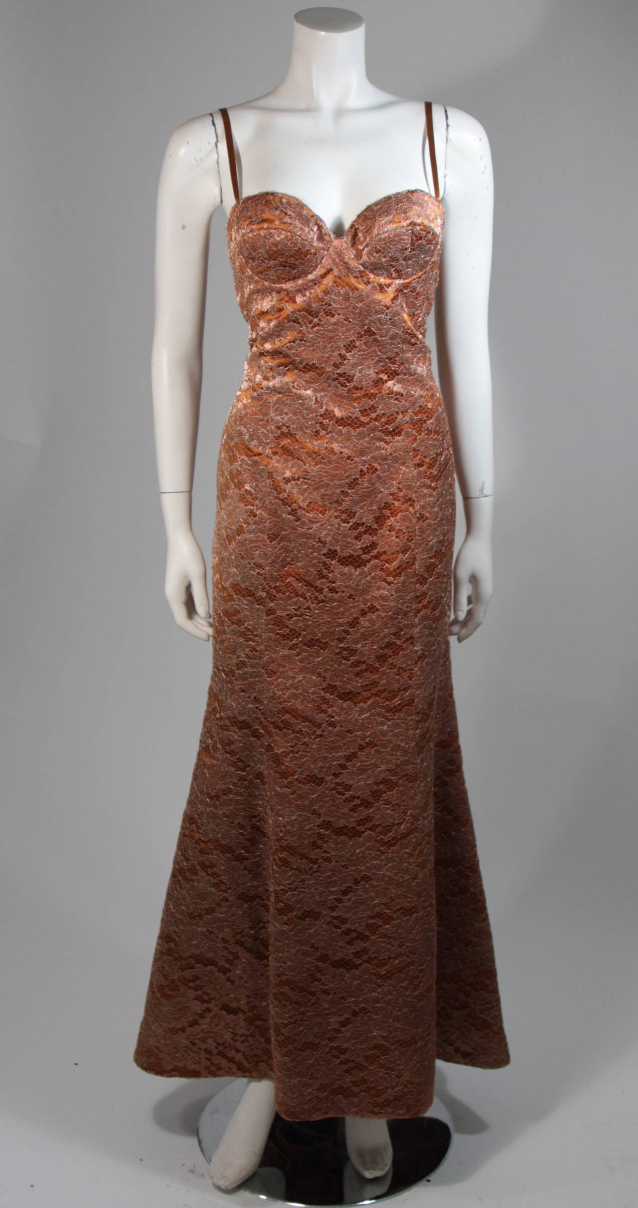 This Escada Couture design is available for viewing at our Beverly Hills Boutique. We offer a large selection of evening gowns and luxury garments.

This gown is composed of a bronze and gold metallic lace a top a bronze satin. The gown features