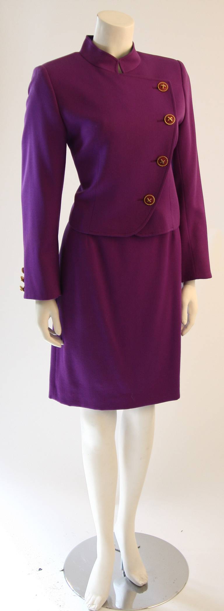 This is a wonderful Valentino skirt suit. This two piece suit features a gorgeous jacket with mandarin style collar . Accented with lovely gold and purple buttons. The skirt is a classic pencil shape with zipper closure. Made it Italy.

Measures