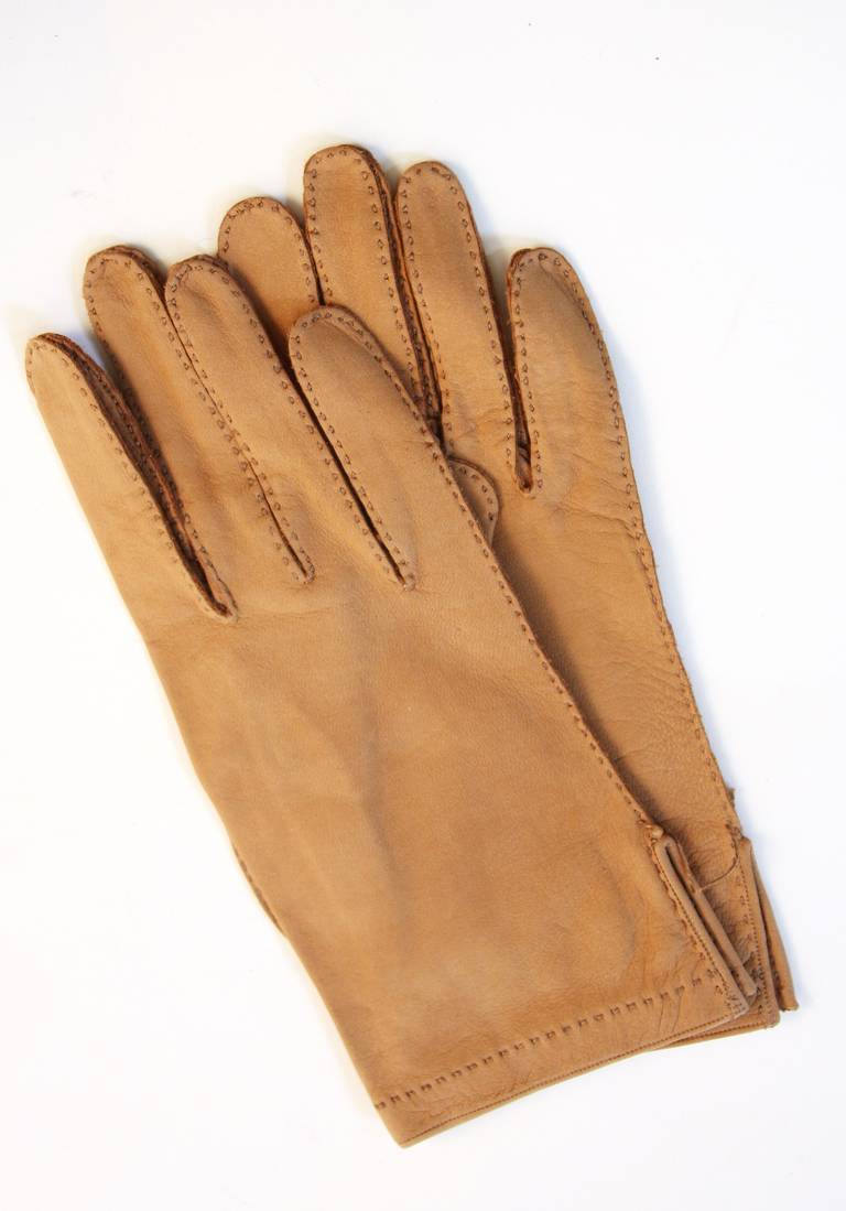 This is a pair of unworn Hermes gloves. They are constructed of a beautiful supple leather in tan and feature a brilliant yet understated top stitch detail. Made in France. 

Measures (Approximately)
Wrist: Flat  3 7/8