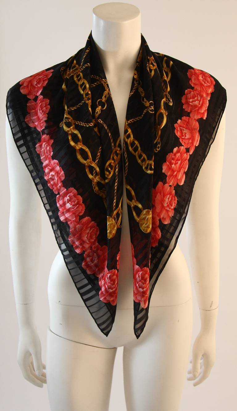 This is a gorgeous scarf by Chanel. The black superbly soft silk is cloaked in an arrange of roses and gold hued chains. Accented by satin textures and metallic strips. Fabulous scarf. Made in Italy. 

Measures (Approximately)
34