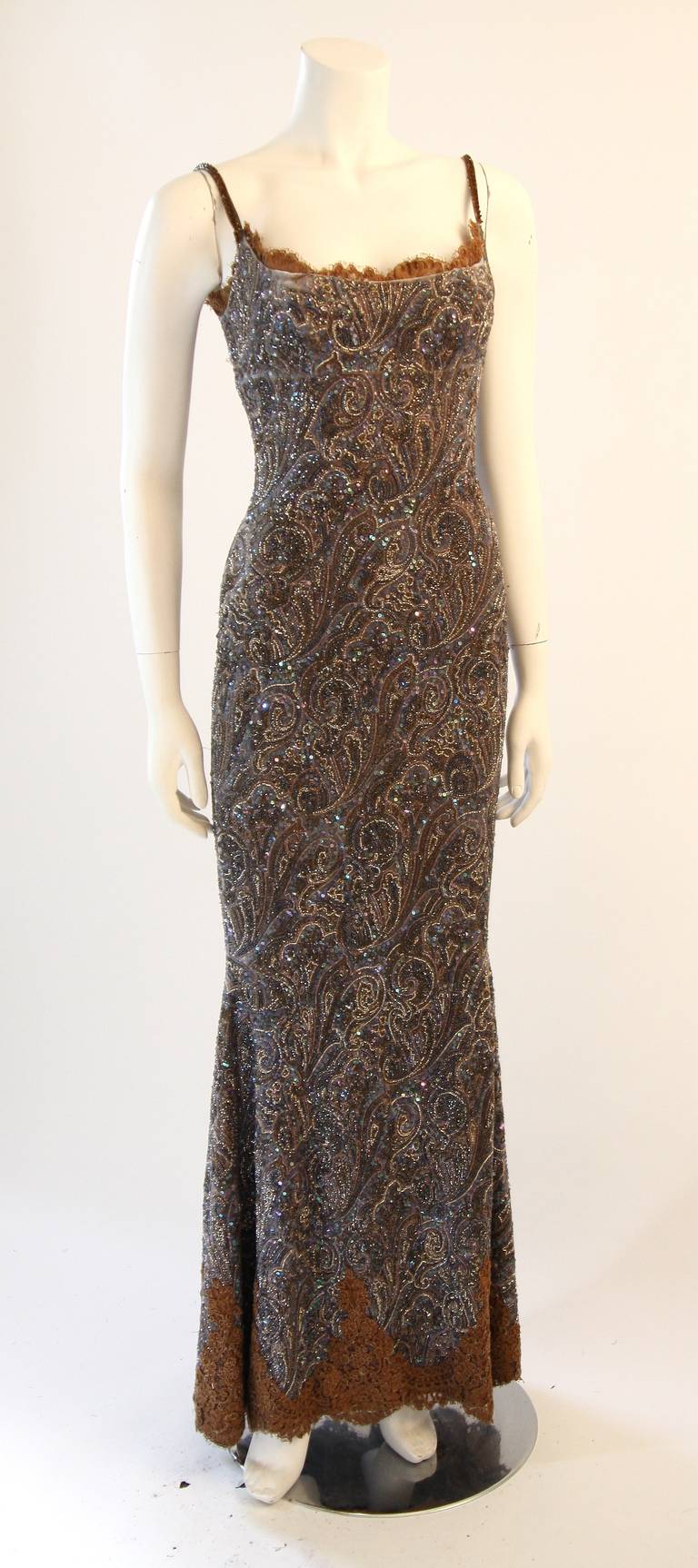 This is an exquisite Randi Rahm gown. The gown is a beautiful spaghetti strap design with brown lace trim. It is composed of a paisley print velvet embellished with beads and rhinestones. Features a side zipper for ease of access. Shown with an