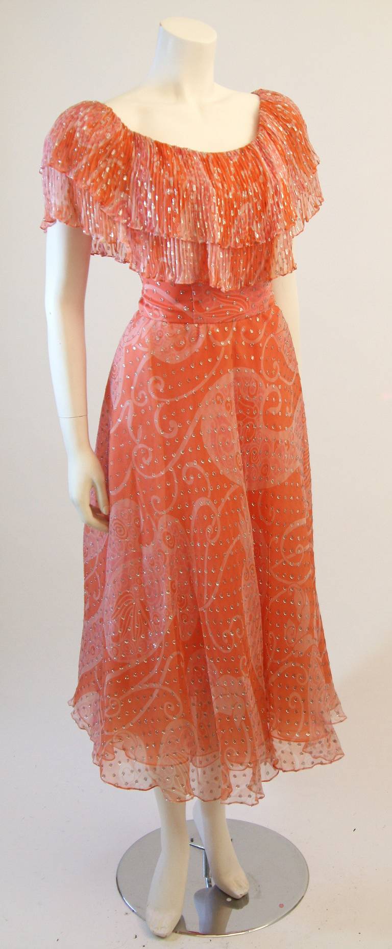 This is a wonderful Diane Dickerson. This dress is composed of a wonderful coral silk chiffon with a mixture orange cream hues. The off the shoulder design is is accented with a pleated ruffle and accompanied by great flare style skirt. 

Measures