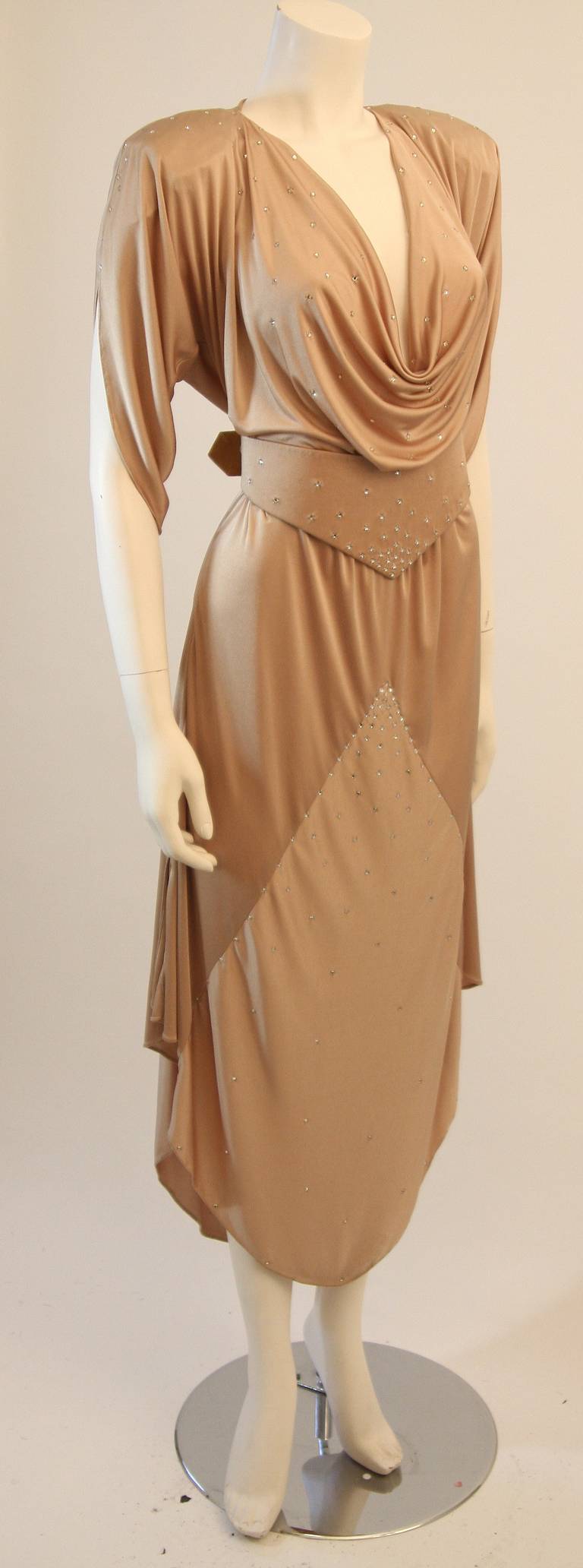 This is a gorgeous evening dress by Brigitta. The dress is composed of a great champagne jersey that is embellished with rhinestones. The dress features a beautifully draped sleeve and bust. Comes with belt.  

Measures (Approximately)
Length: