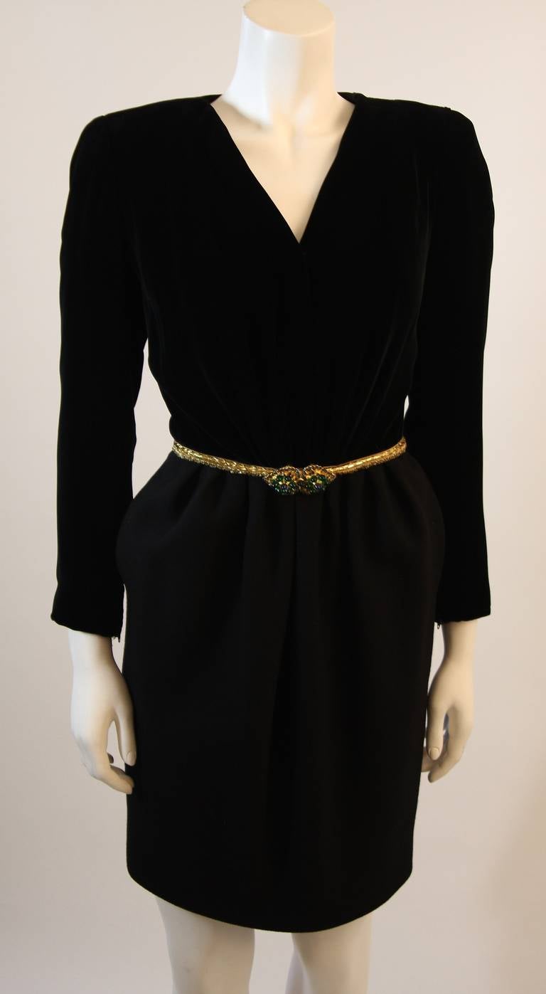 This is a stunning Oscar De La Renta cocktail dress. This dress features a draped velvet bodice with a plunge neckline complimented by a gorgeous wool skirt, with pockets. The waist has a gold faux belt accented by emerald and jewel toned