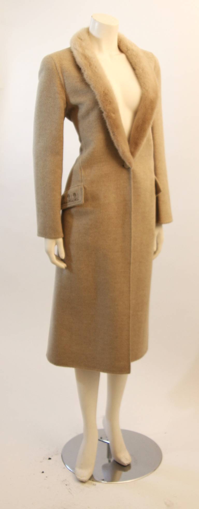 This is a wonderful Valentino coat. The coat is composed of the most supple wool blend and an ultra soft mink collar. It features a brilliant fur trim, two front pockets (unopened), and a center front button fastening. Interior has a striped