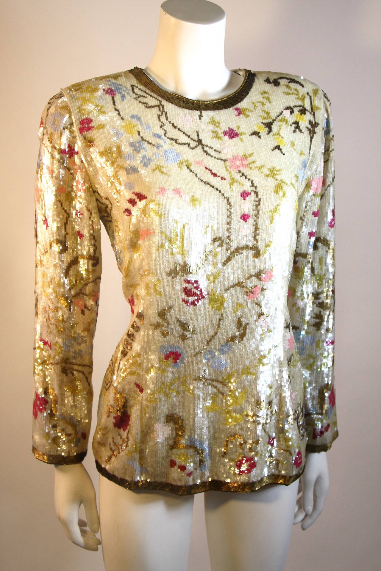 Show stopping cream silk sequin with iridescent gold cast sequins with deep to light pink floral design blouse. Contrasting antique gold sequin trim adds dimension to this already stunning piece by Oscar de la Renta.
Hidden back zipper, Made in the