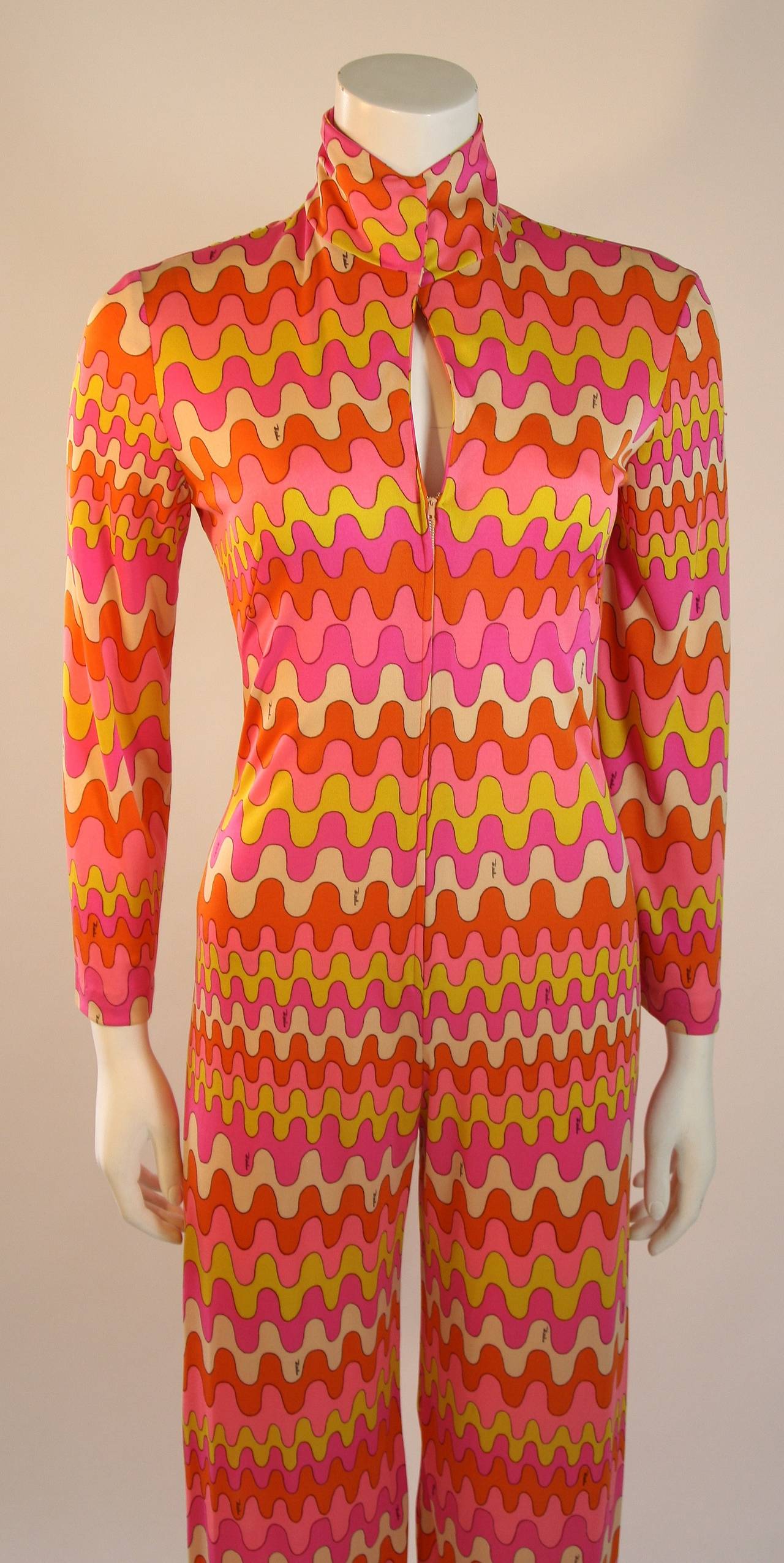 This is an Emilio Pucci design. This wonder jumpsuit features a center front zipper and snap neck closure. The suit is composed of a stretch jersey in orange, pink, and yellow hues. Made in Italy. 

Measures (Approximately)
Length: 58.25
