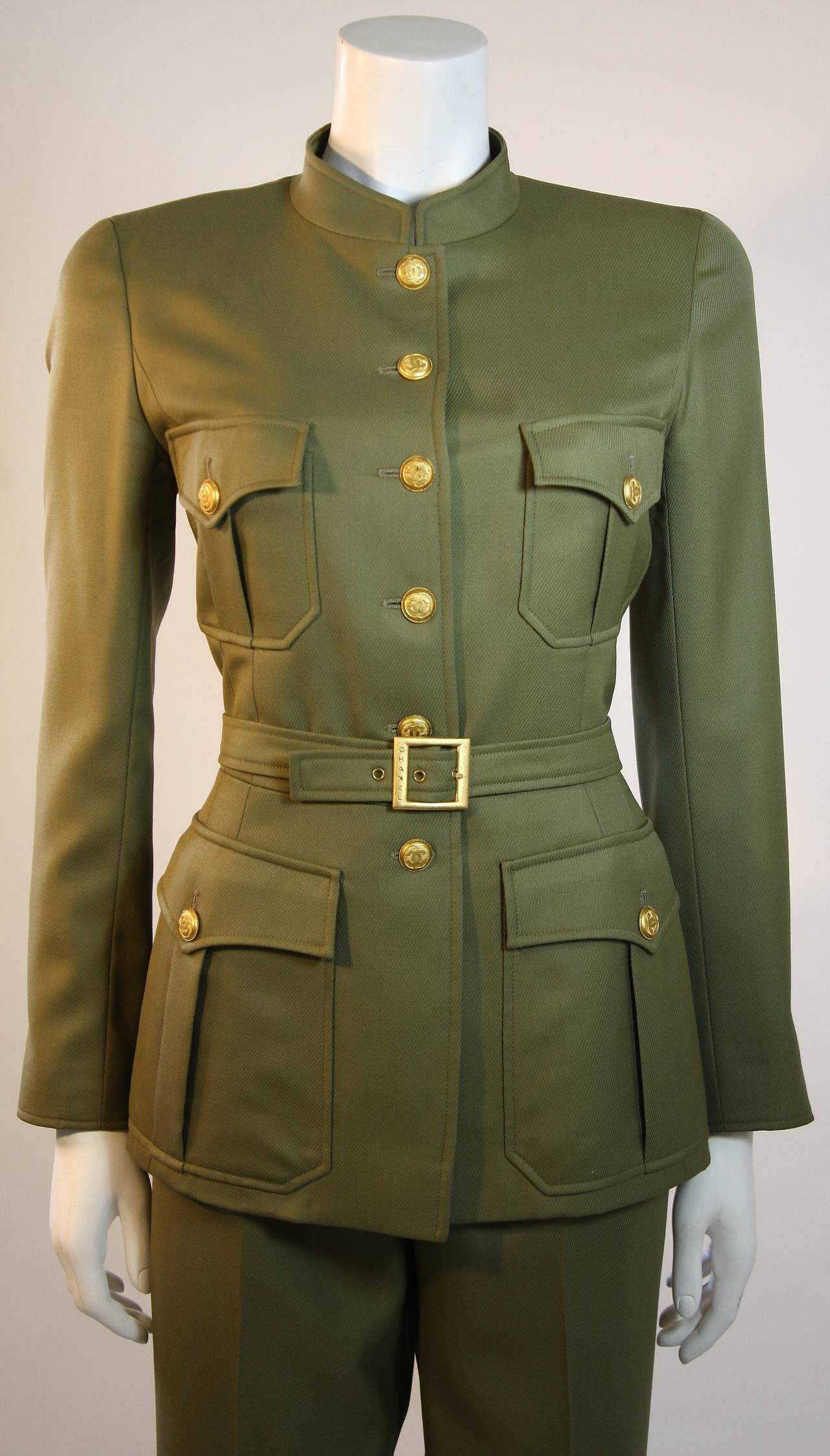 Fabulous lightweight army green wool with a ribbed texture akin to silk faille, lined in silk, two piece suit by Chanel Boutique, 96A. The fitted waist jacket boasts 16 gold linked C buttons down the front, on the pockets, and cut detail cuffs. The