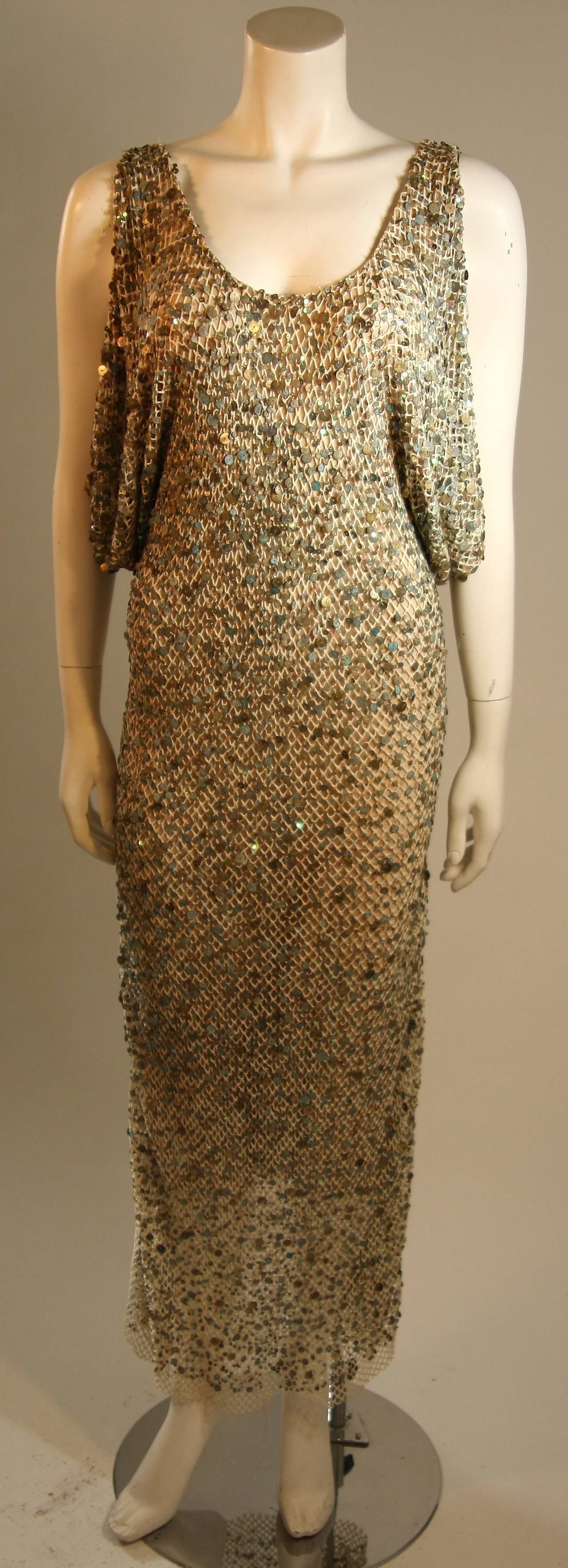 This is a Heike Jarick design. This dress is composed of a mesh layered with a thick/wide weave cotton that is embellished by weathered paillettes. The color of the embellishments range from an aqua to white and bronze. This dress has a stunning